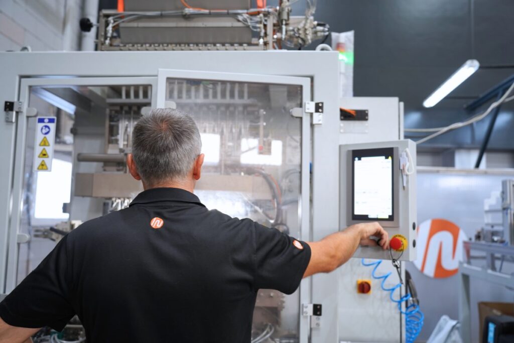 INVpack technician commissioning and adjusting a packaging machine on site.